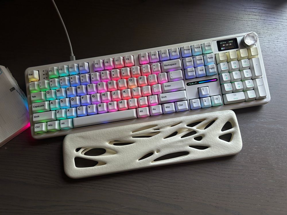photo of a white keyboard with rainbow backlighting and white wrist rest