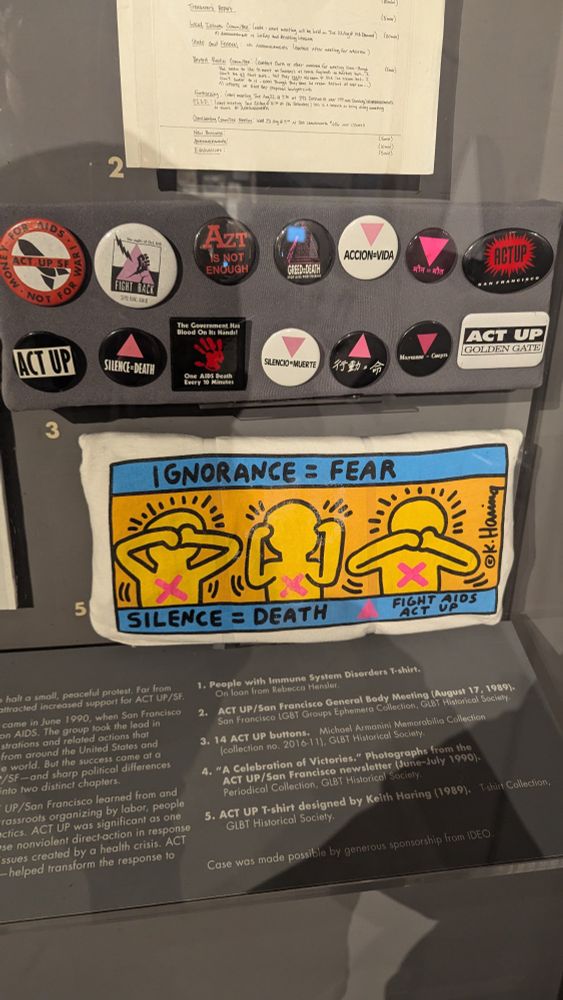 Top: selection of ACT UP + Silence = Death pins. Bottom: ACT UP, silence = death tshirt designed by Keith Haring