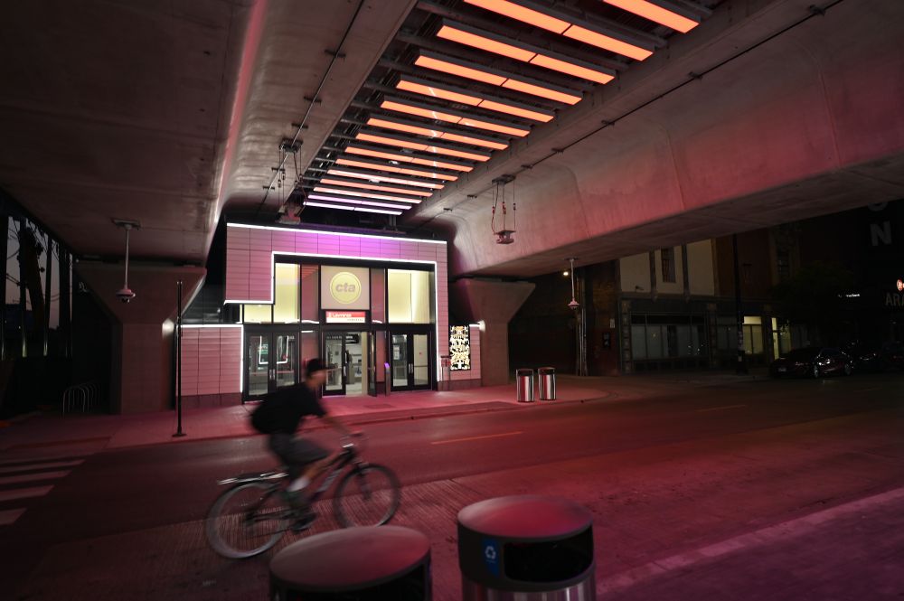 The Lawrence station at night with a bike blurred going past, with horizontal bars of light at the top