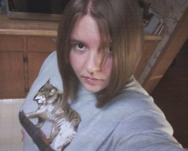 Mid 20-something Antares wearing a grey sweater with a wolf on it.