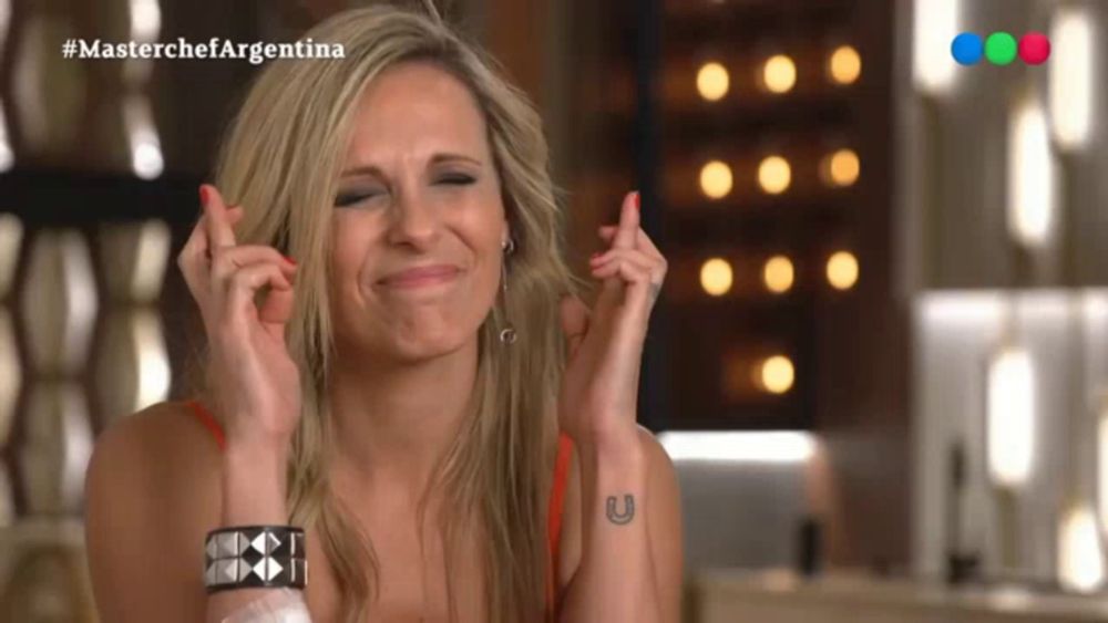 a woman crosses her fingers in front of a screen that says masterchef argentina on it