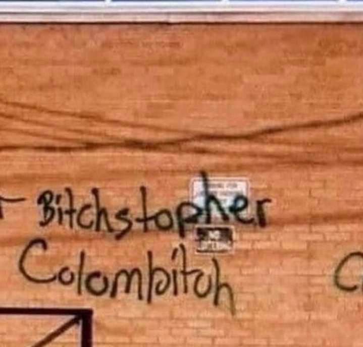 A nicely messy scrawled graffiti on an orange brick wall: Bitchstopher Columbitch