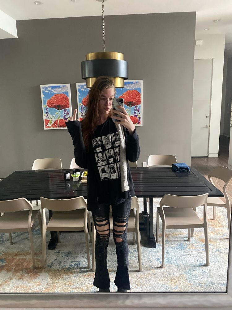 valerie is standing in front of a mirror wearing all black and flipping off the camera