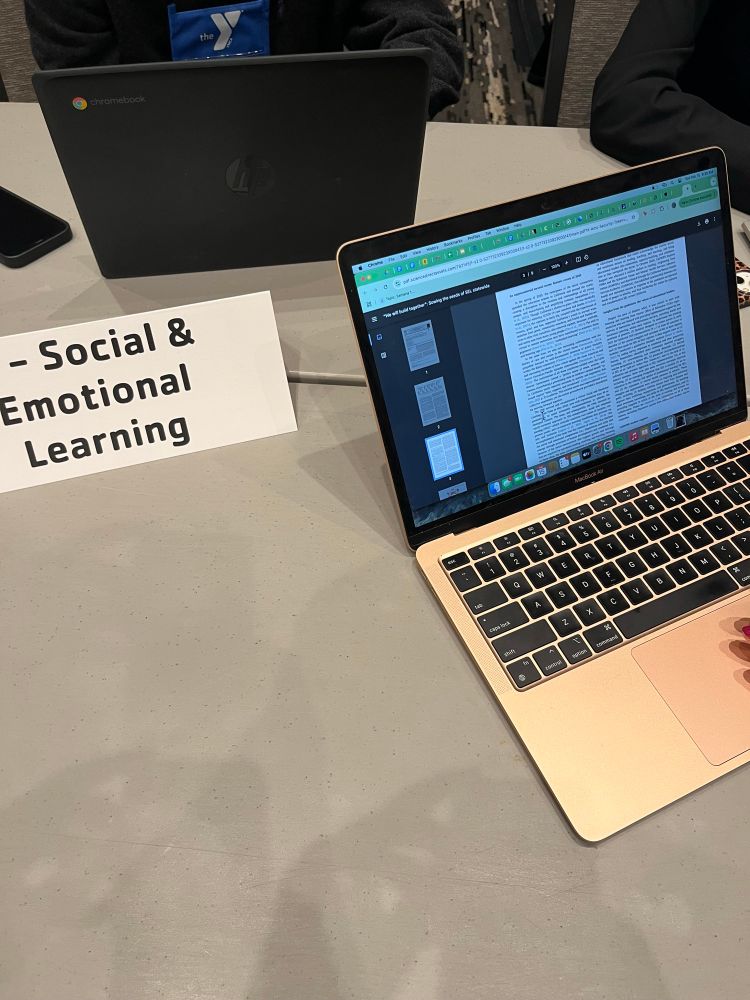 Laptop with an article on its screen and a white placard next to the laptop that reads “social and emotional learning” 