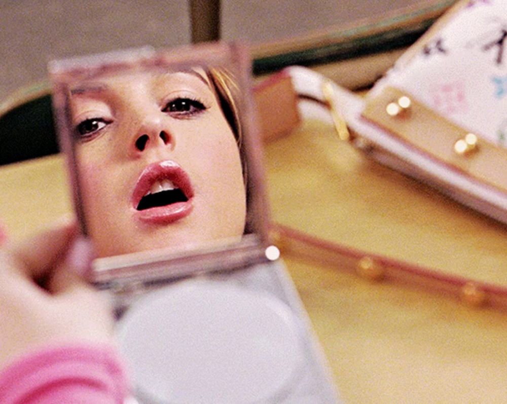 a woman is looking at her face in a mirror with her mouth open