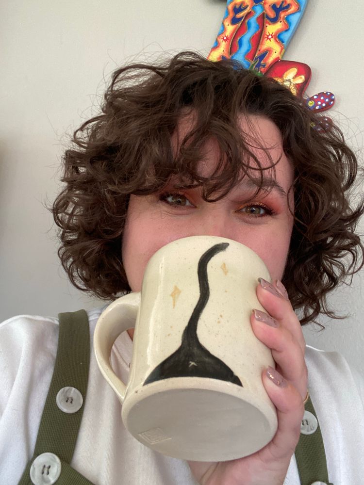 OP holding the mug to show the back. It’s a black cat’s backside, complete with tail, sparkles, and a butthole. ✨