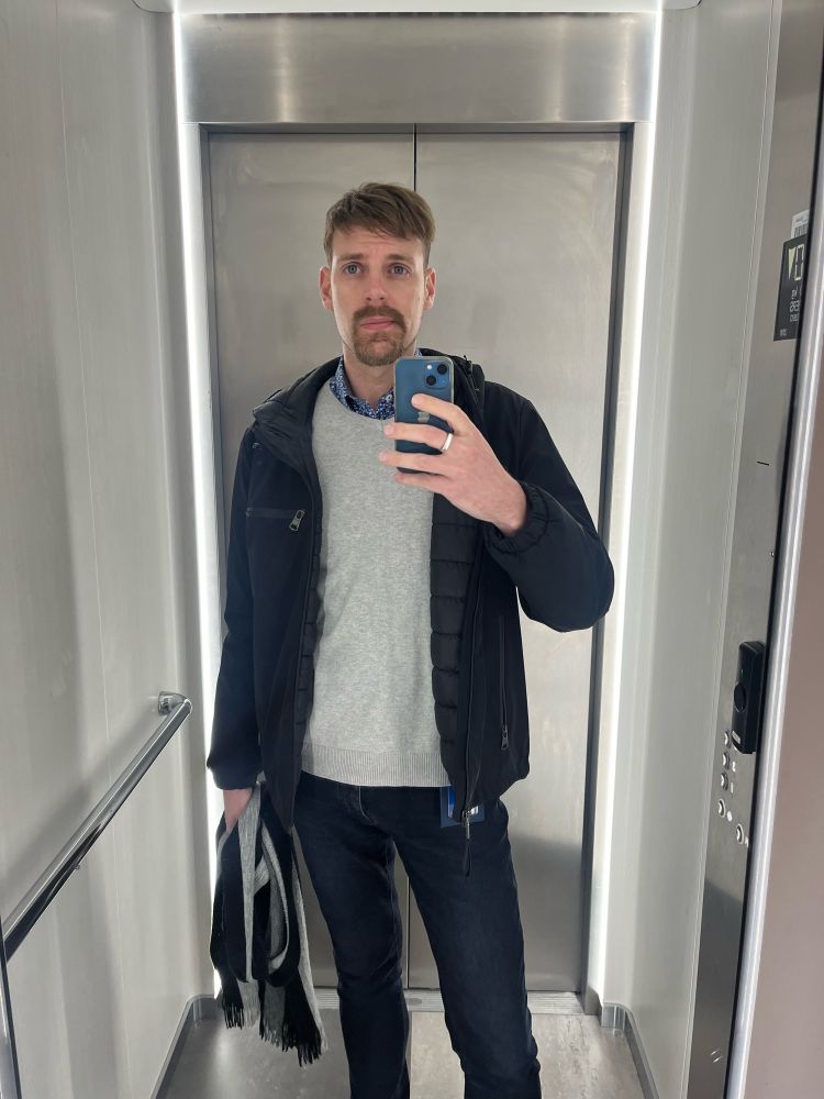 Homme au look discutable en fin de journée de taff prenant un selfie dans un ascenseur