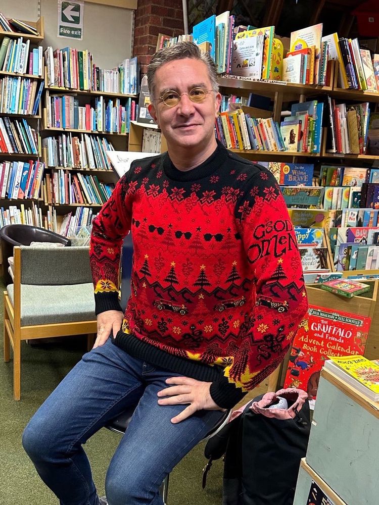 Rob Wilkins, a dapper fellow in a red good omens Christmas sweater that I will be stealing shortly