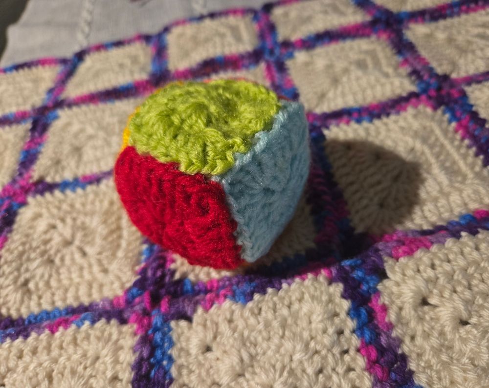 Multi color hand crochet dice sits on top of crocheted game board