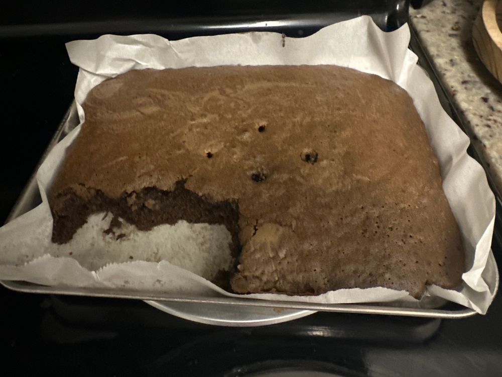 a tray of slightly eaten brownies, with some holes poked in the center and the bottom left corner missing