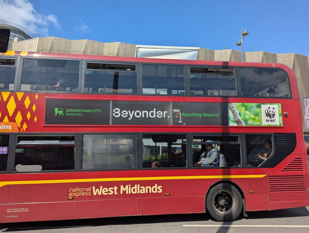 a double decker bus with an advert for Birmingham City University, which says "Beyonder. Reaching beyond.".