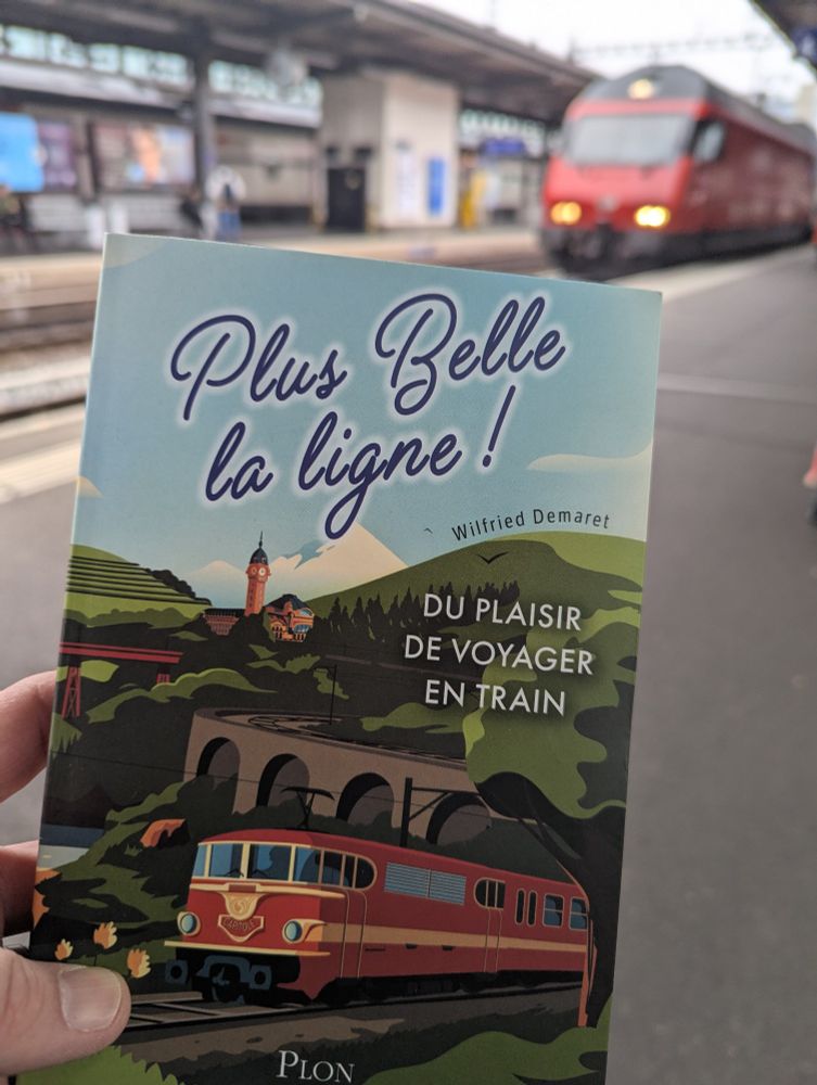 Photo du livre de @bb27000.fr "plus belle la ligne !" sur un quai de la gare Cornavin de Genève avec une locomotive Re460 au second plan. 
