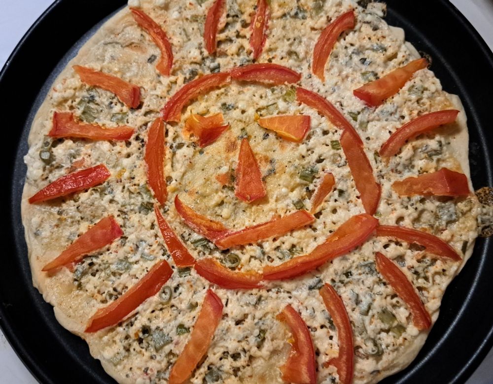 Weiße Pizza 
Rundes Backblech mit Pizzateig belegt mit weißer Soße aus Creme legere, körnigem Frischkäse , ital Kräutern und Frühlingszwiebeln. Darauf eine lachende Sonne aus Tomatenscheiben