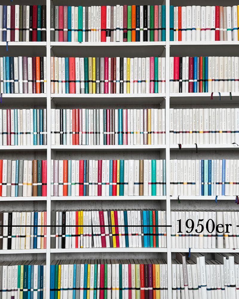 Ein Regal voller Bände der Bibliothek Suhrkamp mit der Jahreszahl 1950er.