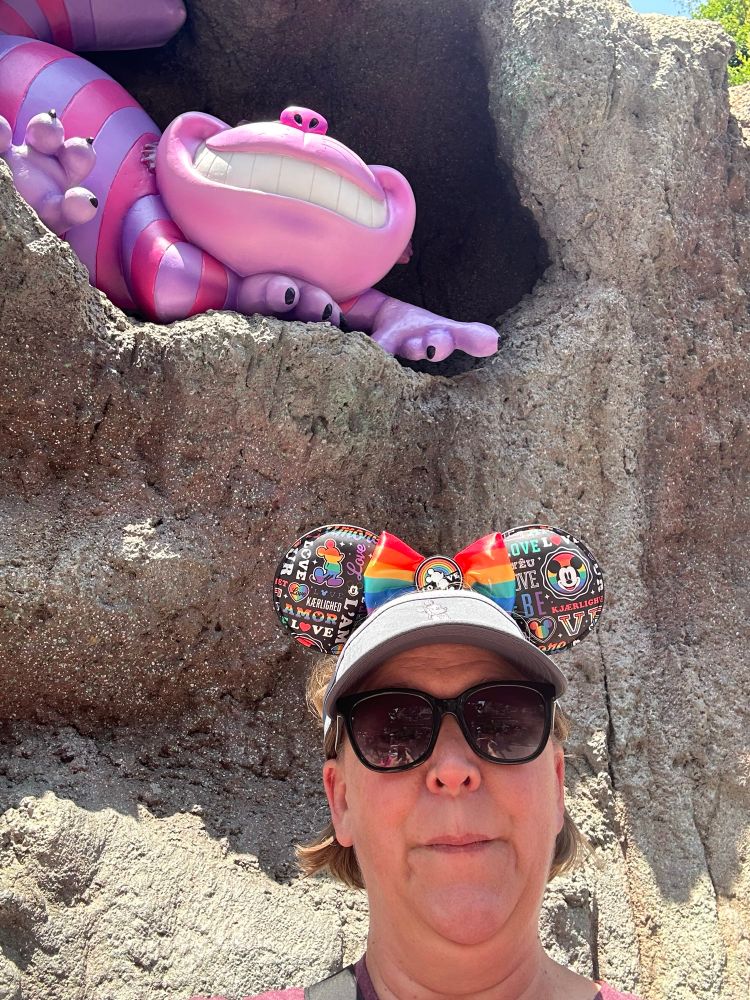 A selfie with the Cheshire Cat at Disneyland. He’s wearing his pink and purple stripes, and I’m wearing sunglasses and Pride ears.