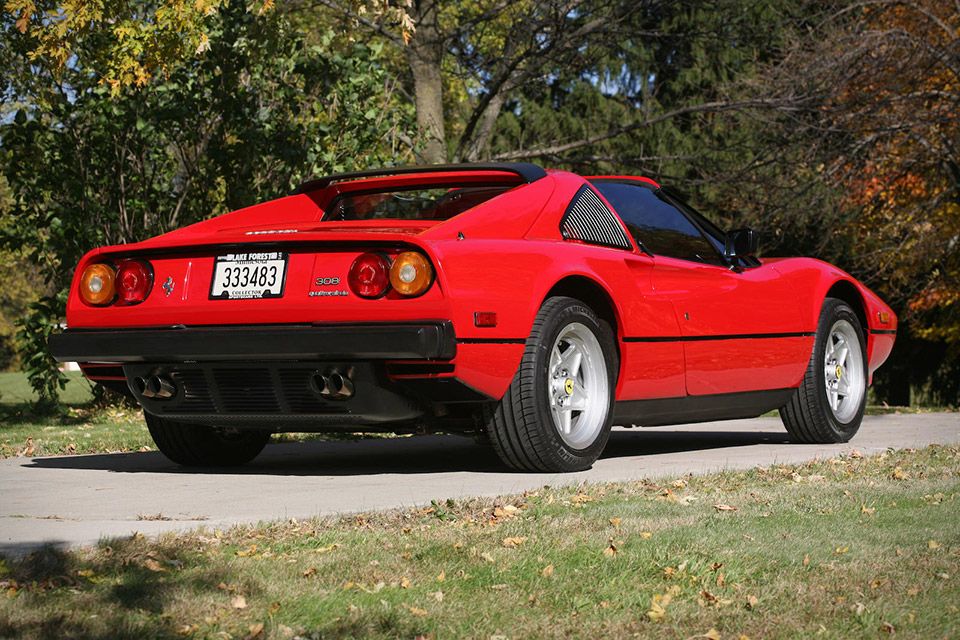 a red Ferrari seen from the back with round taillights and silver wheels.