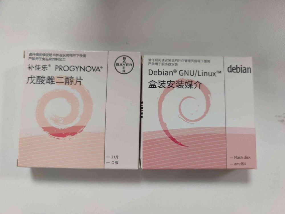a pink and white box labeled PROGYNOVA with a spiral on the box art, of a prescription HRT.  Next to it is a debian box with very similar art (which is probably a mockup as a joke, or a way to camouflage the box for stealth purposes, as HRT is probably illegal in china) 