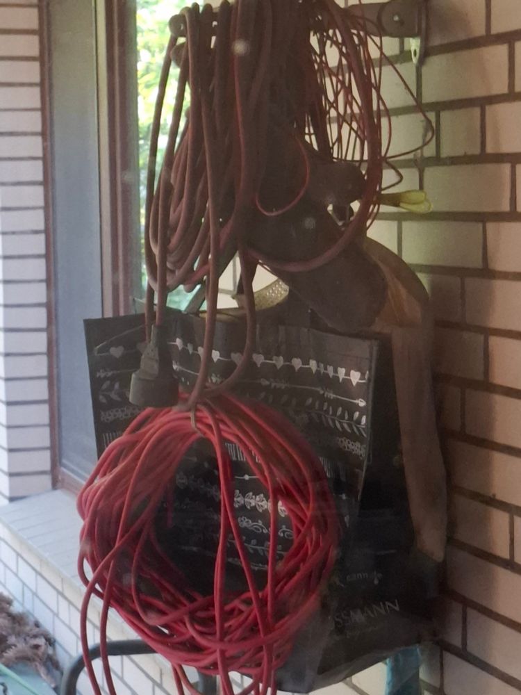 Man sieht ein hängenden Chaos an Kabeln Taschen alte wäscheleine und einem alten grillhandschuh 