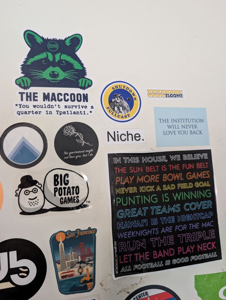 The MACcoon sticker on a wall next to several other Sickos and adjacent themed stickers.