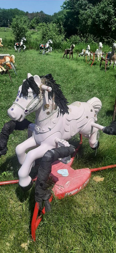 a pale lilac riding horse toy decorated with glitter, in front of a ring of other riding horse toys, which form Ponyhenge.
