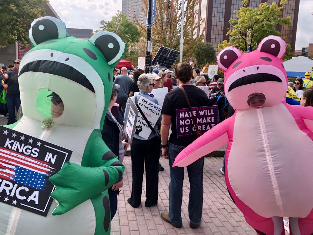 A green frog and a pink frog make their way through the crowd at the No Kings protest in Grand Rapids MI.