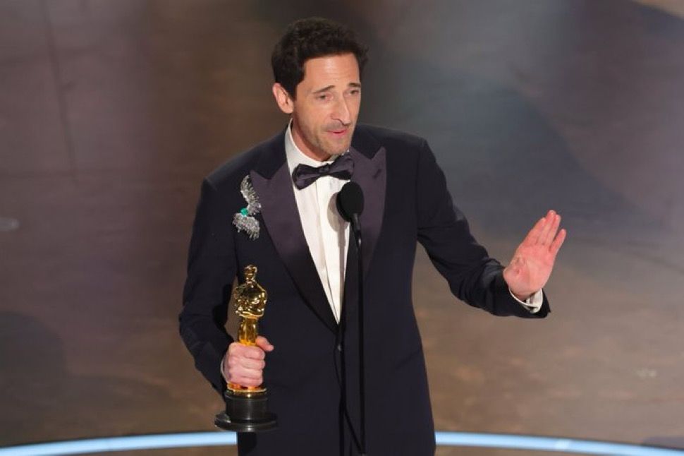 Adrien Brody with his hand up telling the Oscars to turn off the exit music
