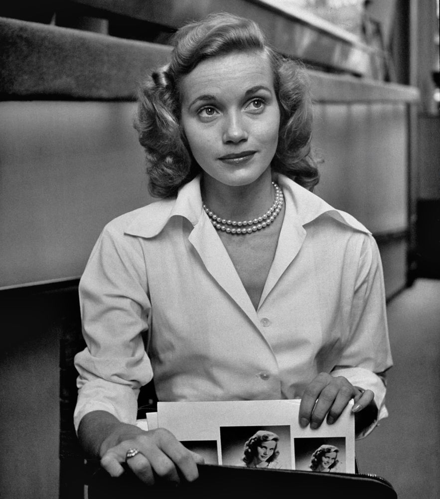 25-year-old Eva Marie Saint in LIFE Magazine in 1949 wearing a white blouse and pearls and pulling her headshots out of a portfolio. 