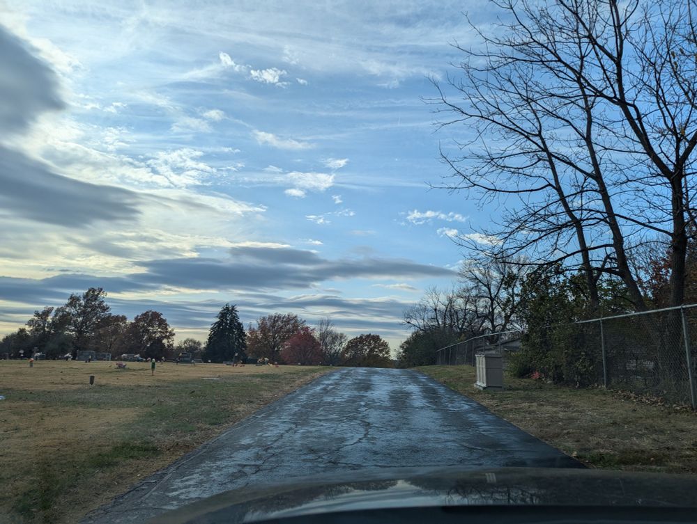 Blue sky with whispy clouds above the cemetery road