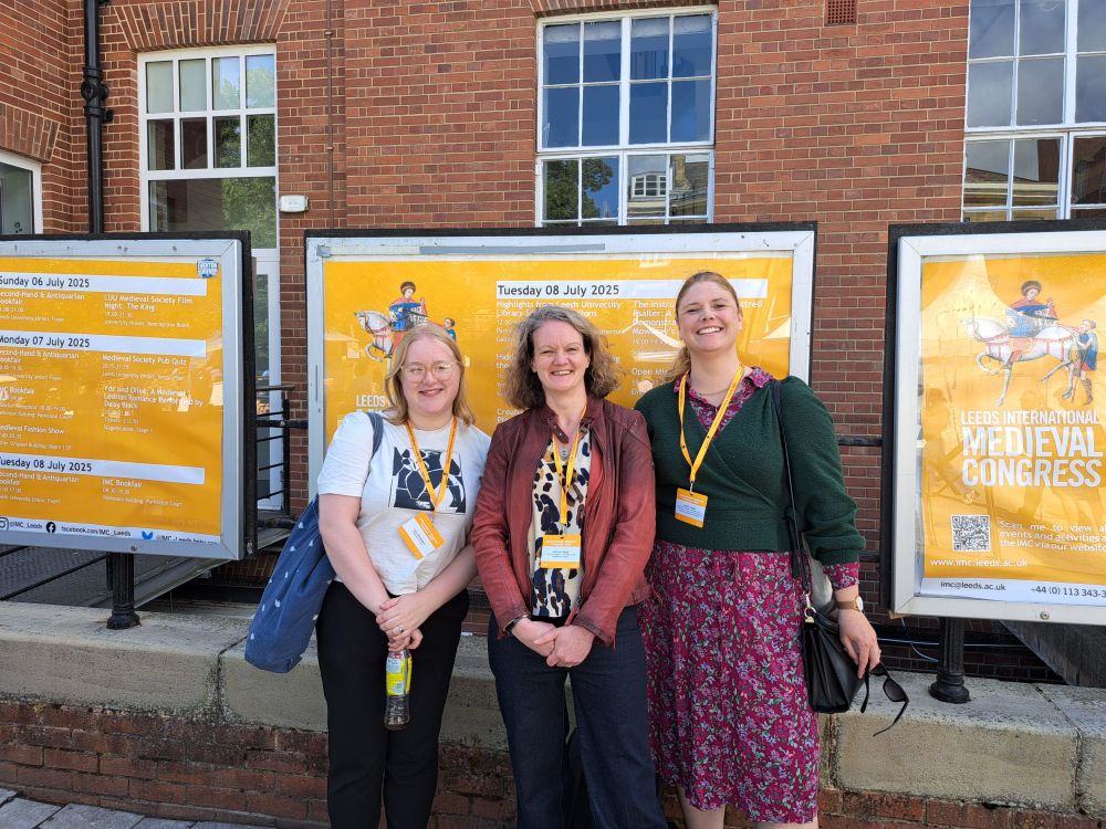 Three Women standing in front of information boards for the Leeds International Medieval Congress
