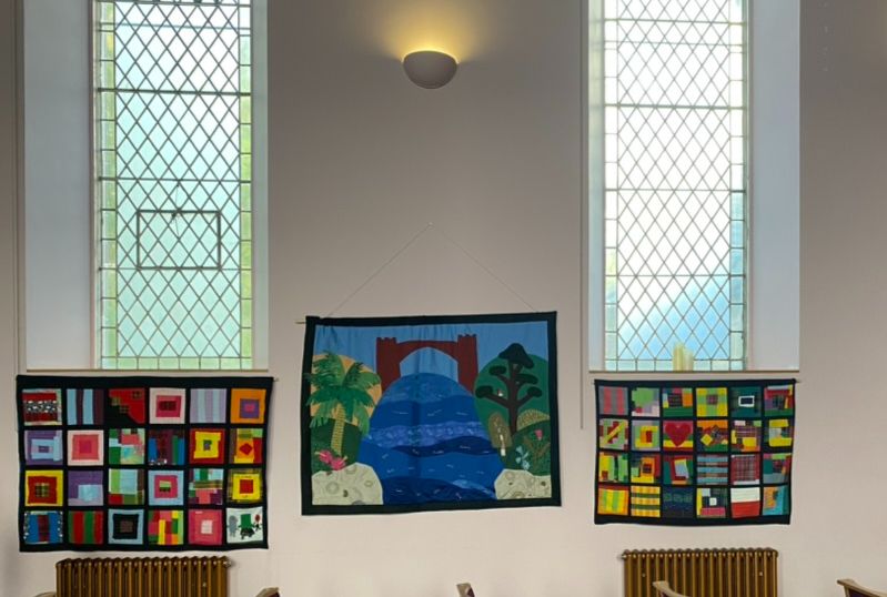 View of the church interior, with three textile banners hung on the wall. 