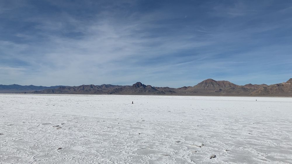 The Bonneville Salt Flats race track. Just white salt on the ground and mountains in the background. A blue sky with whispy white clouds