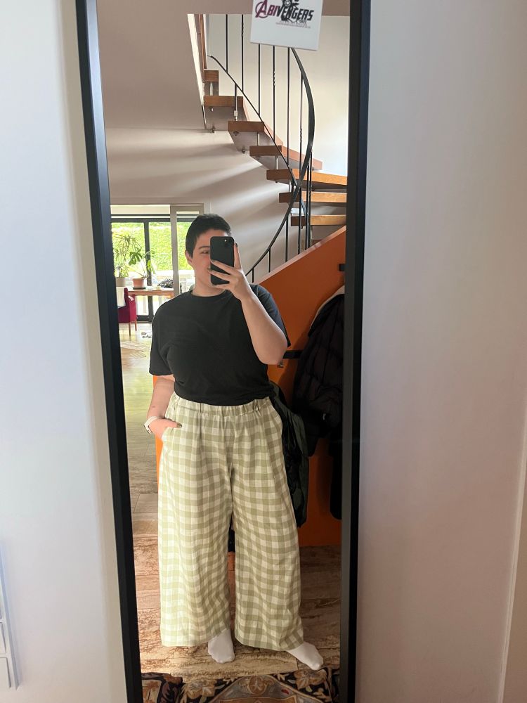 Spiegel selfie einer jungen Frau. Schwarzes T-shirt und grün-weiß karierte Hose 