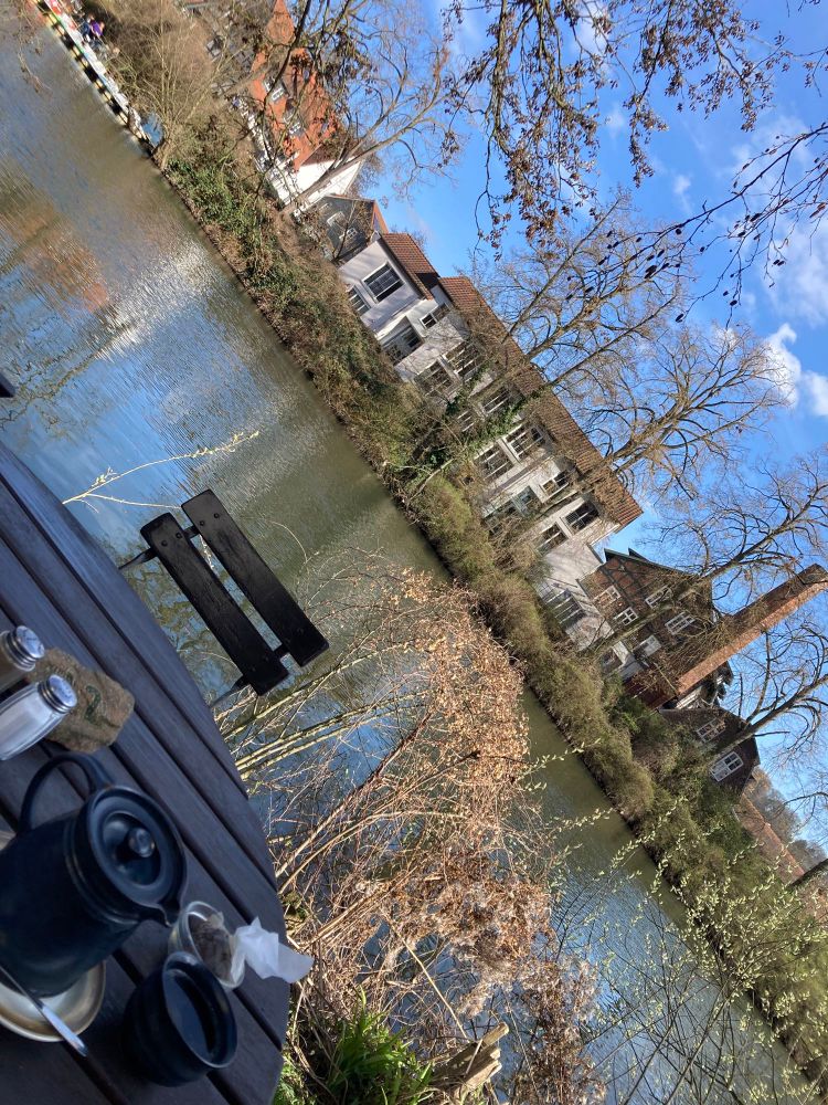 View from a cafe towards the river at its terrace. A cup of black tea, cigarettes, a copy of "a month in the country" by JL Car