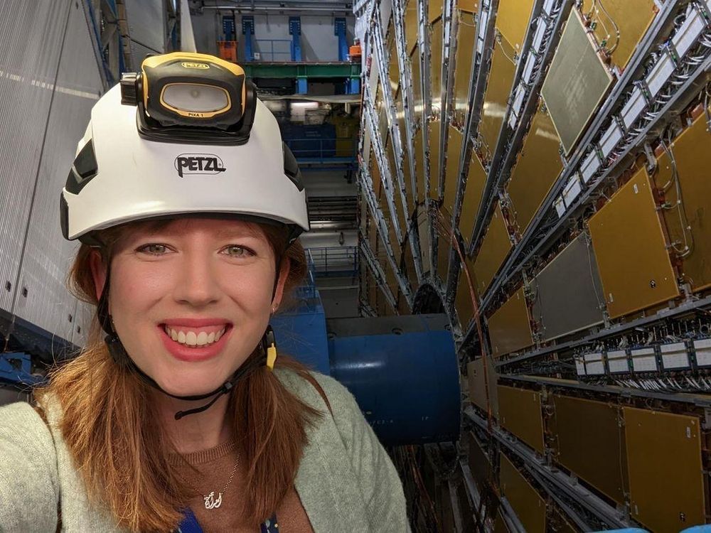 Photo of me smiling in a helmet in front of the ATLAS Experiment at CERN