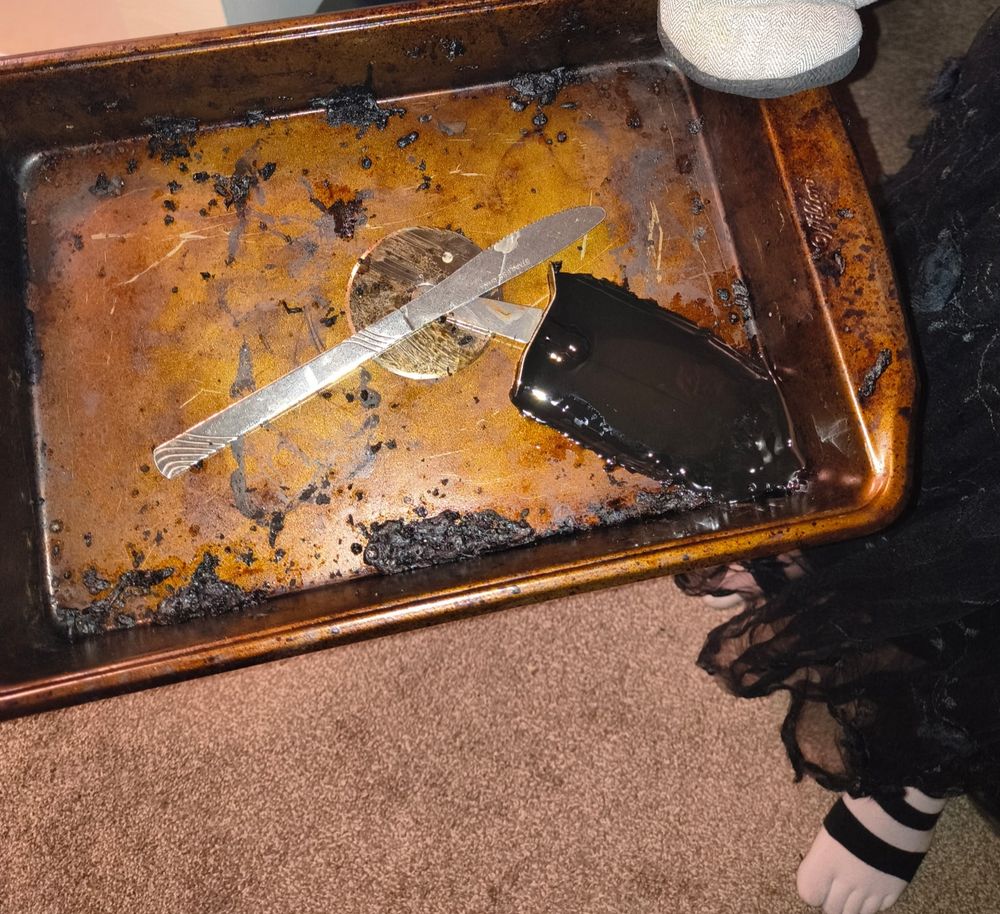 Fucked-up pan with melted pizza cutter handle and also a knife