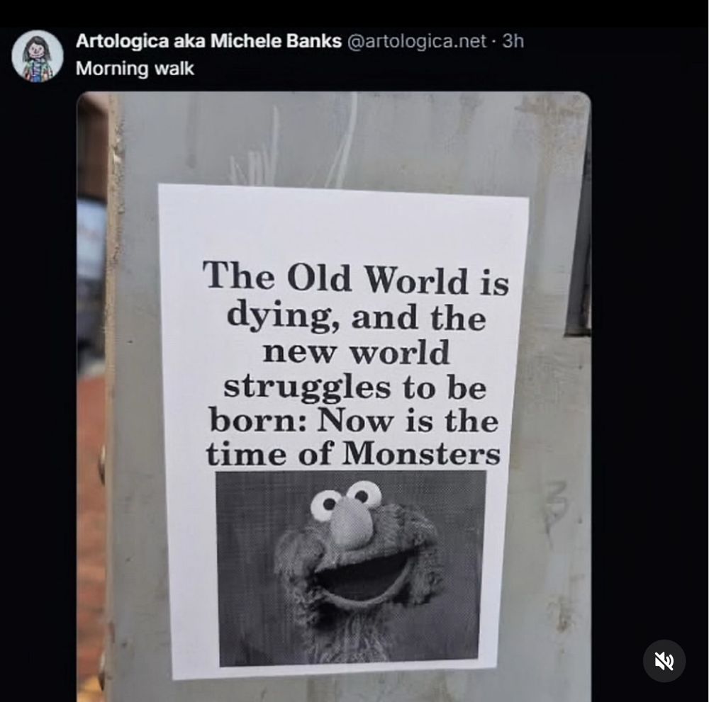 Photo of a flyer pasted to a wall in a city. It reads: The old world is dying and the new world struggles to be born. Now is the time of monsters” above a picture of smiling muppet Elmo.