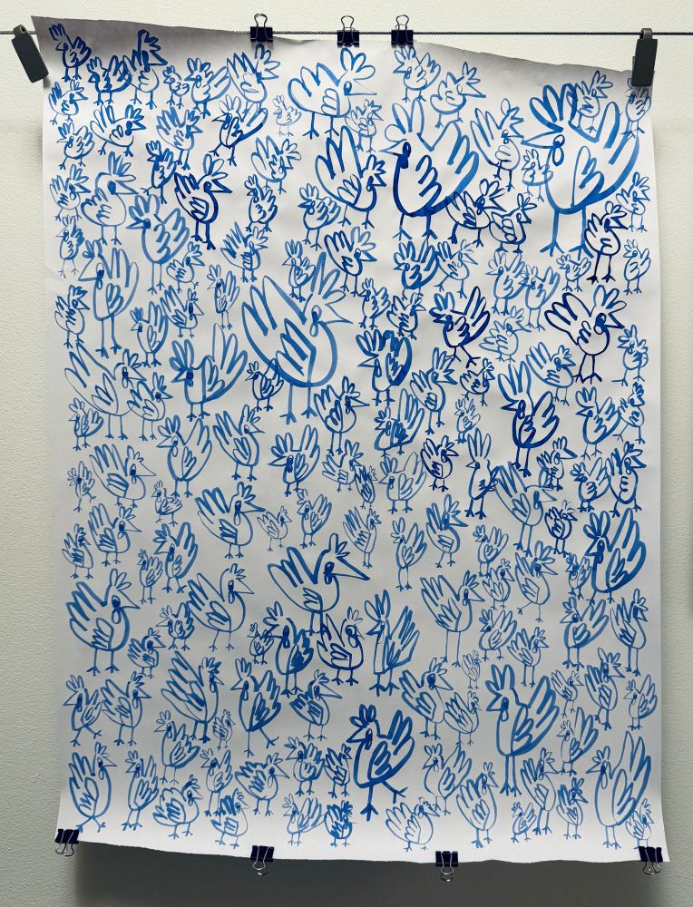 A large white sheet of paper hangs from a wire. There are many doodles of chickens drawn across the surface of the paper.