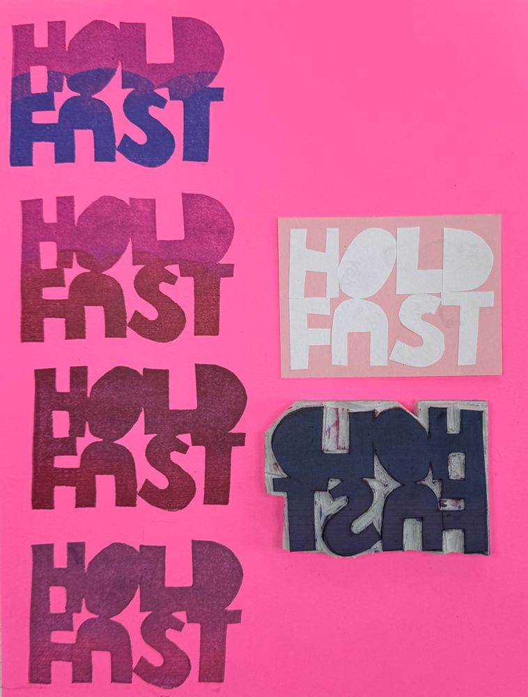 A crudely cut rubber stamp with the words “hold fast” has been stamped on the left-hand side of a vibrant pink piece of paper. The stamp and inspiration hand cut letters are on the right hand side.