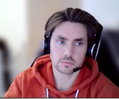 Screenshot Lars Butnotleast (mir) im Microsoft Tesms Meeting - Webcam Sicht Fenster ausgeschnitten.

Ich sehe müde aus und trage ein headset und einen roten (oder dunkelorangenen) Hoodie mit weißen Bändeln - ich schaue leicht zur Seite, müde aber niedlich und die Haut sieht durch die webcam sehr glatt aus - wie oben beschrieben trage ich einen kurzen Vollbart, aber nicht sonderlich dicht wuchernd. 

Der Hintergrund ist verschwommen 