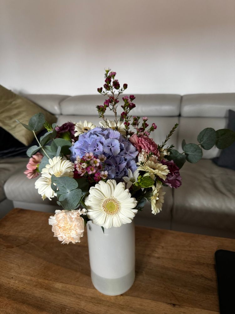 A pretty flower arrangement with a blue hydrangea and marguerites