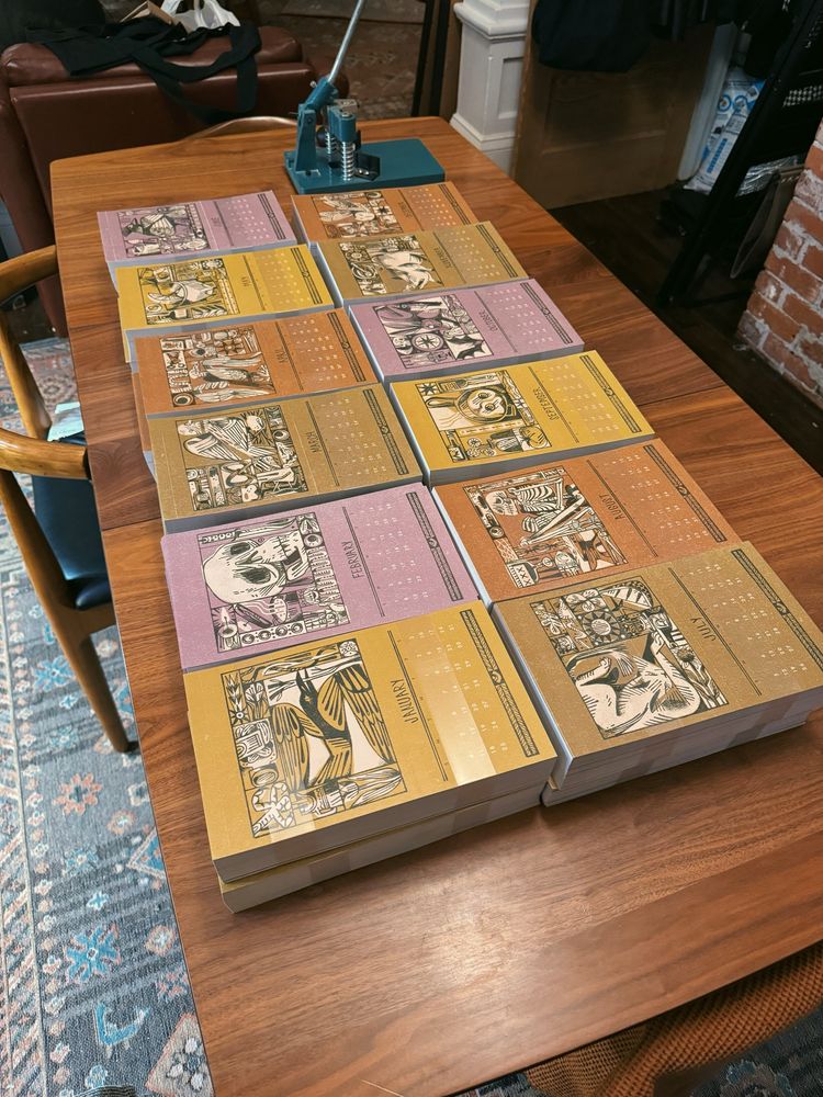 A photo of a dining table covered in stacks of printed calendar pages, ready to be assembled 