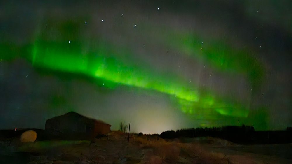 Nordlichtstreifen, im Vordergrund links eine alte Scheune