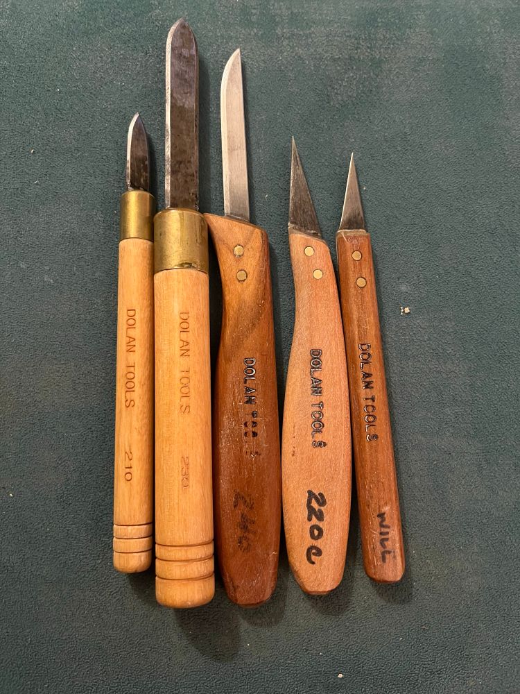 Five Dolan Tools knives on a green table