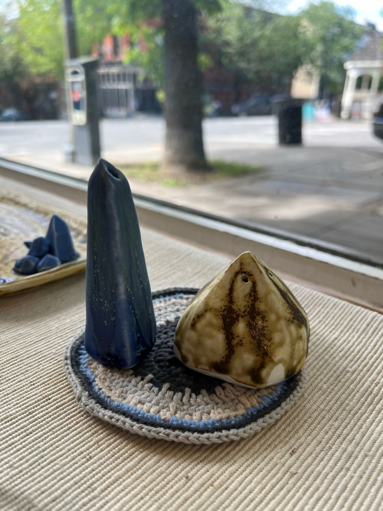A blue obelisk pepper shaker and an amber pyramid salt shaker sit on a blue, black, and white coaster. 