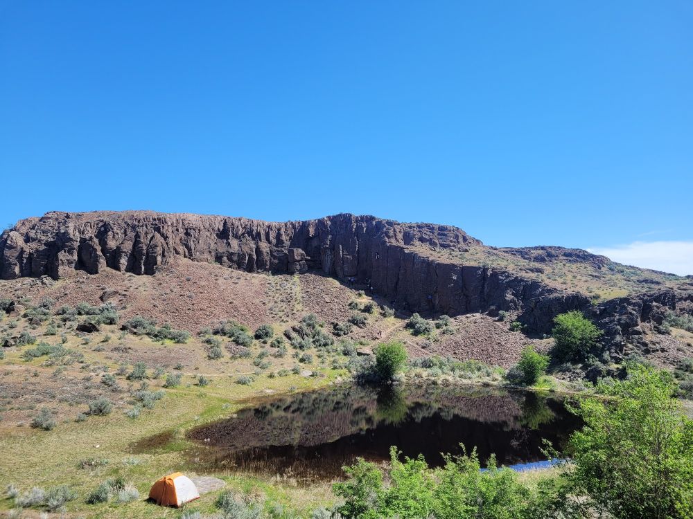 Scenic photo if Cliffside and green valley  with pond. 