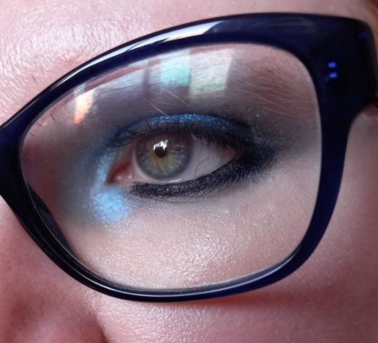 A picture of Fefy's eye with blue and black eye makeup, framed by her glasses 