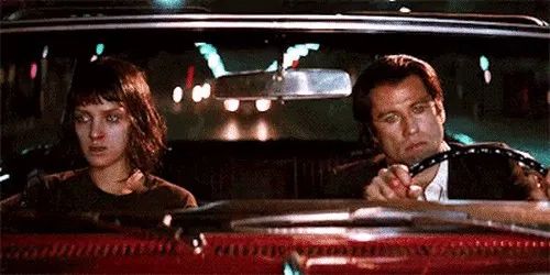 A still from the 1994 film “Pulp Fiction” where John Travolta and Uma Thurman sit silently in a car after a rough substance-fueled night. They’ve been THROUGH it, and it shows.