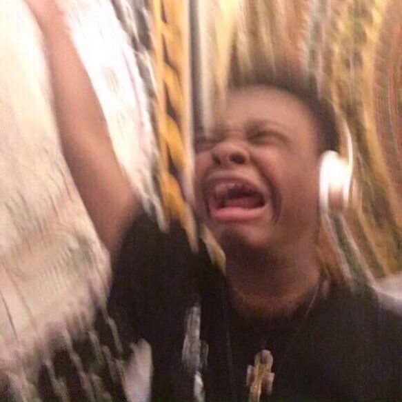 a young man wearing large headphones screams along to his favorite songs with his right arm raised to the heavens, clearly feeling the lyrics in his very soul.