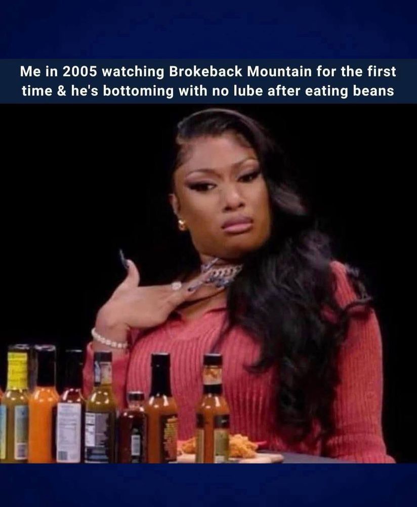 rapper Megan Thee Stallion sits behind a row of hot sauce bottles, her hand gently touching her upper chest, and a look of mild shock and concern on her face. The caption reads: “Me in 2005 watching Brokeback Mountain for the first time & he's bottoming with no lube after eating beans."