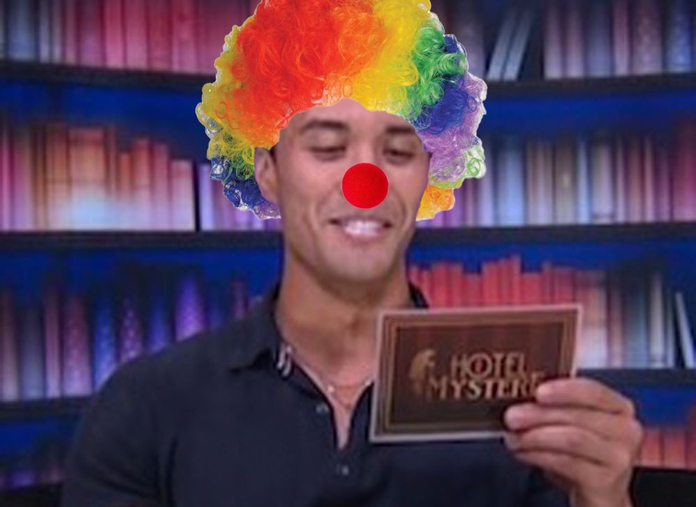 BB27 Zach with a clown wig and nose, in the diary room holding the card that explains his $10k veto power. 